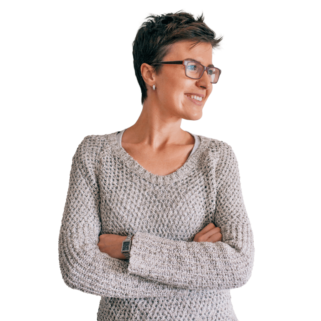 Woman in glasses smiling to the side with her arms crossed.